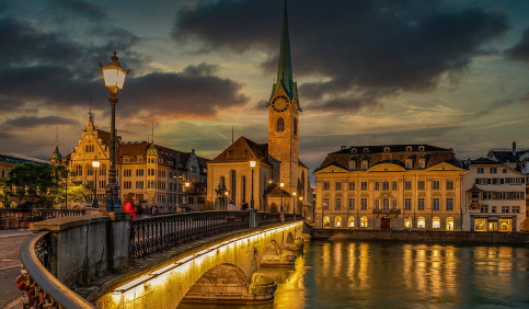 zurich old town bridge limmat river grossmunster church sunset city lights reflection